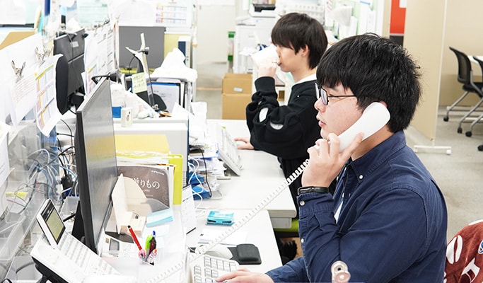 事務作業の様子。男性従業員が電話対応尾をおこなっている